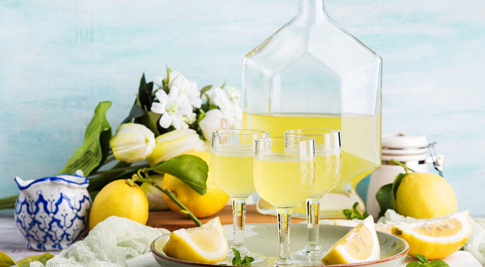 Glasses of limoncello on a tray with lemons