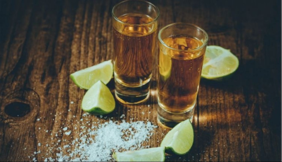 Two gold tequila shots with salt and lime wedges 