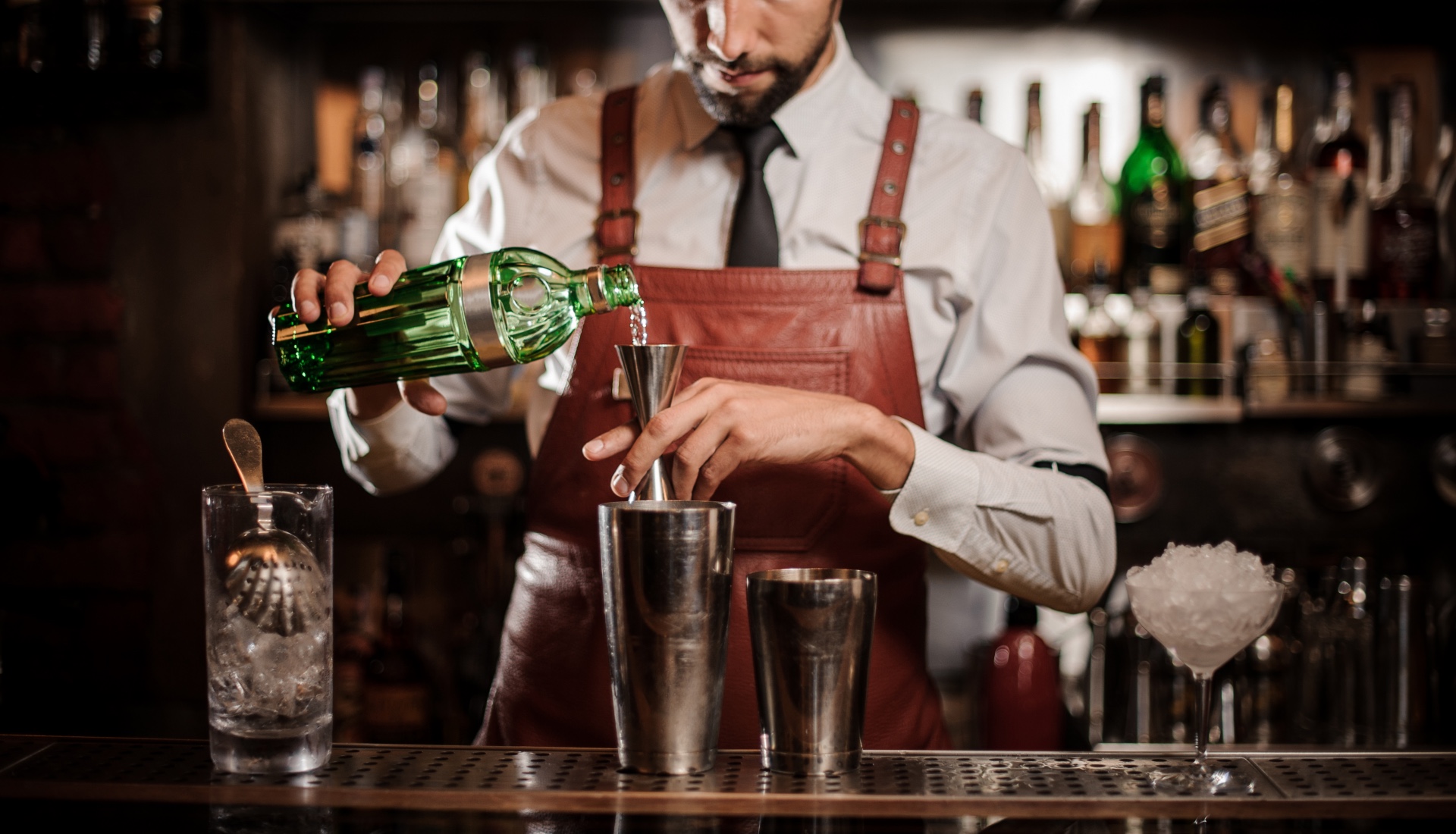 bartender measuring cocktail with jigger