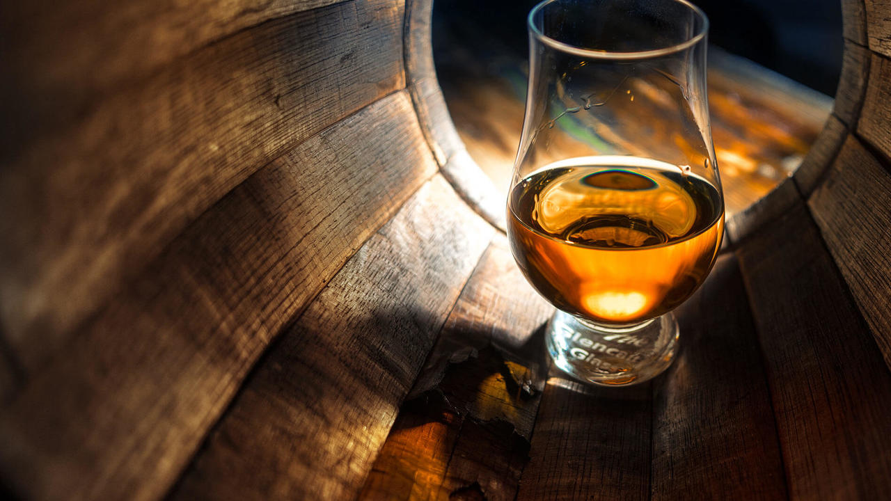 Glass of scotch whisky inside a barrel
