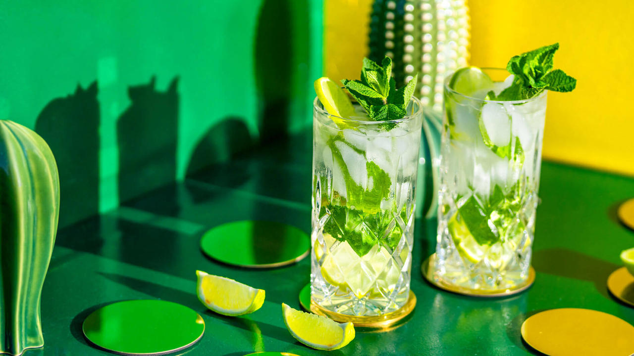 Two non-alcoholic mojitos served on a green table