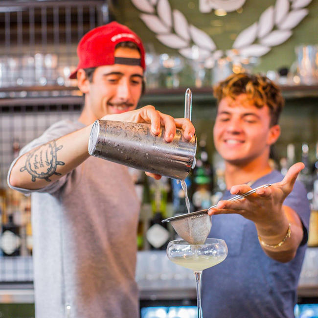 Deux étudiants qui s’entraident pendant une formation de barman à l’EBS Cours international de Barman.